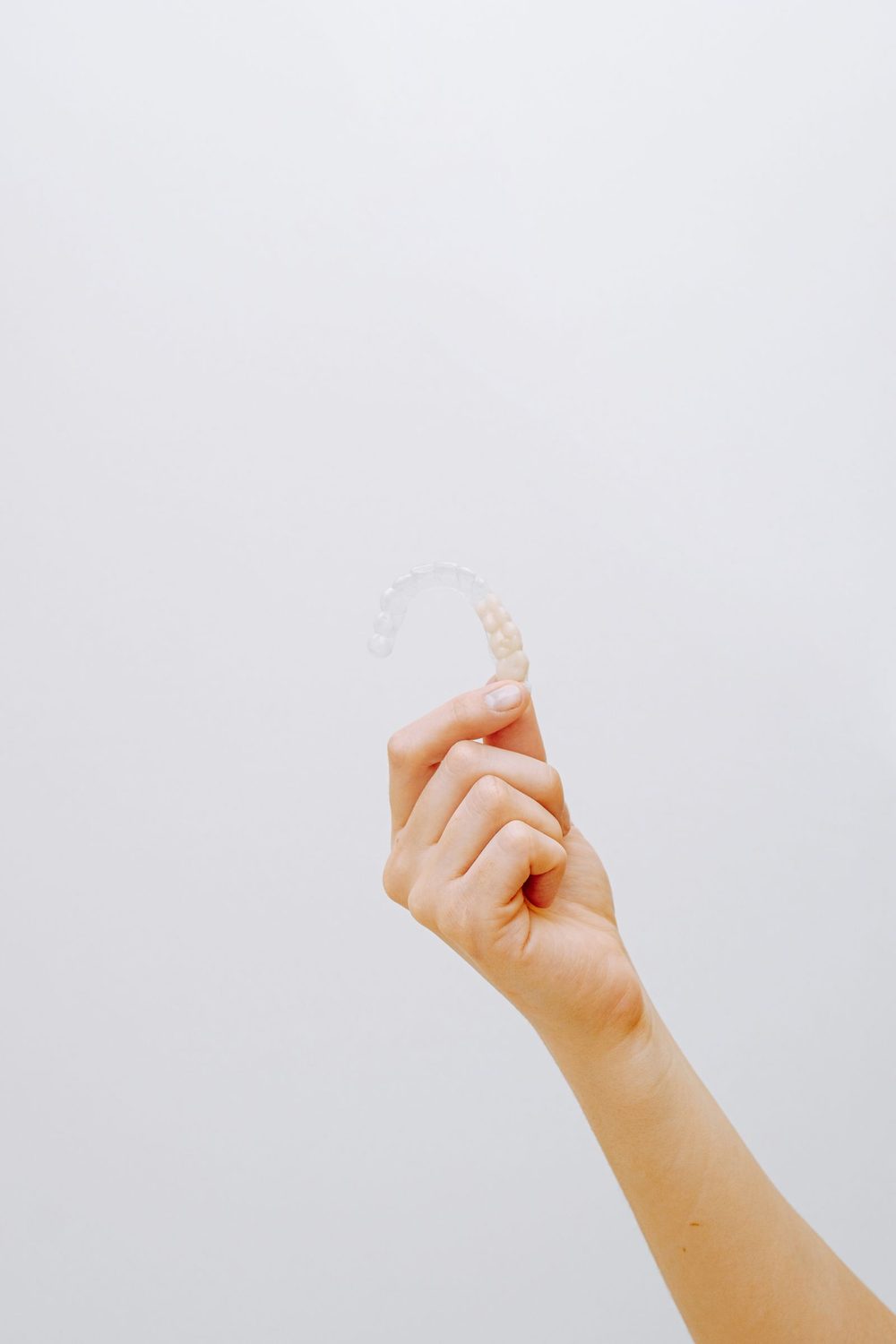 A clear dental aligner held in one hand