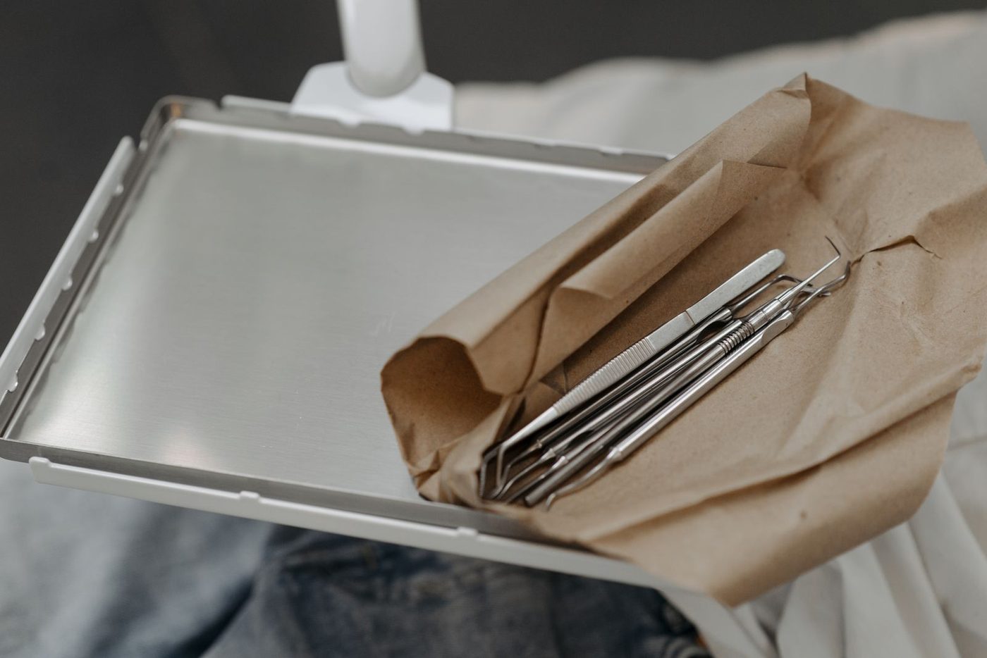 Sterile dental instruments wrapped in paper on a steel tray